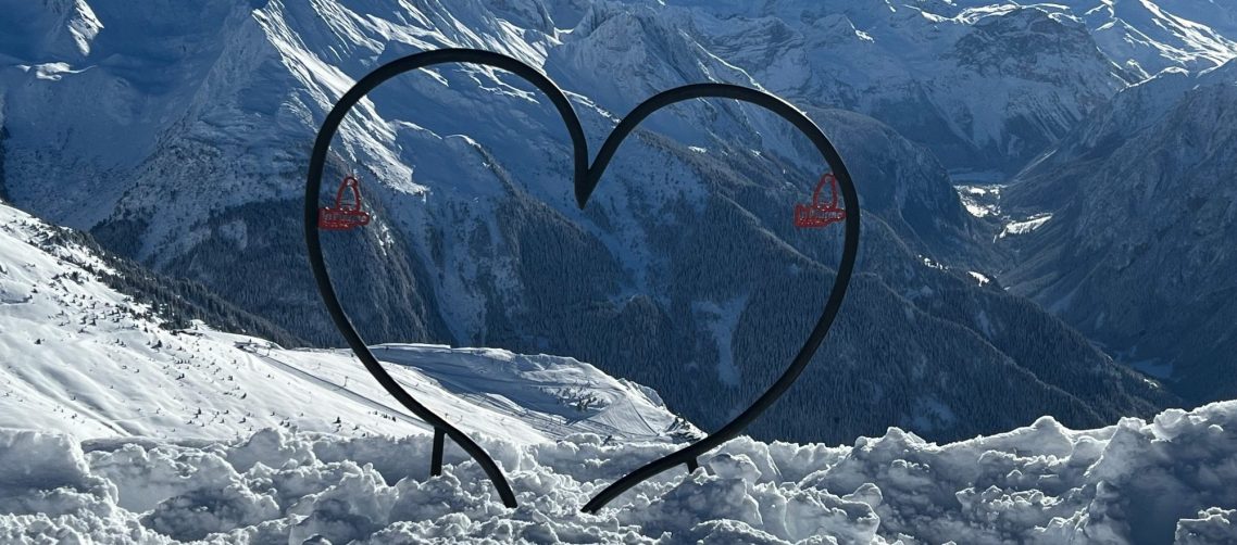 Svart hjärta över snöiga bergstoppar med röda detaljer.