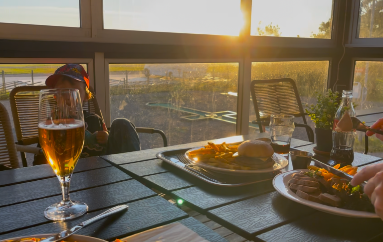 Bord med mat och dryck i solsken, med utsikt över grönska.