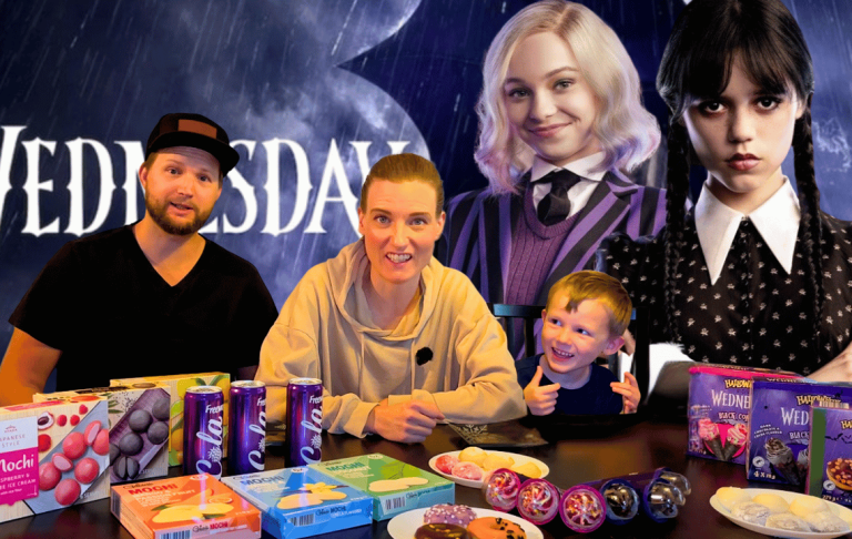 Tre personer (the swilderness family) sitter vid ett bord med bakverk och snacks, med karaktärer från "Wednesday" i bakgrunden.