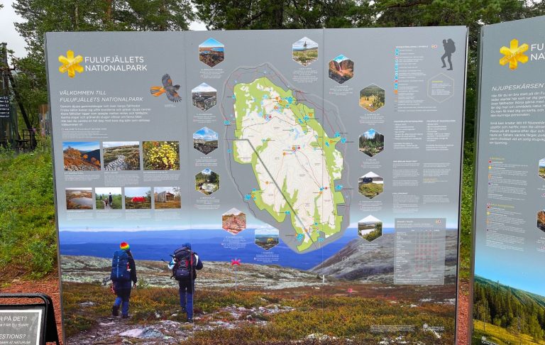 Informationstavla med karta över ett naturreservat och bilder på växter och landskap.