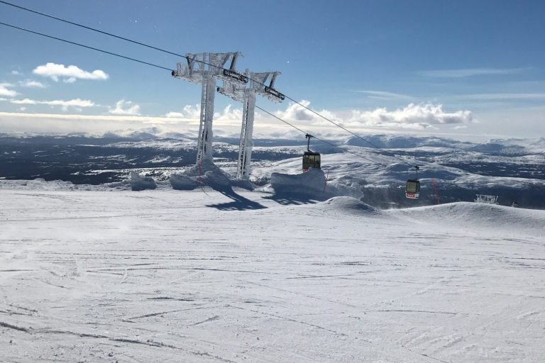 Skidbacke med stolslift och snötäckta landskap under en klarblå himmel.