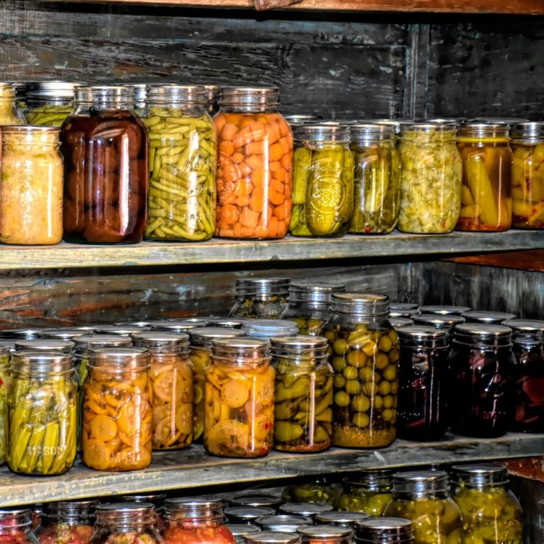 Fyllda glasburkar med inlagda grönsaker på hyllor.