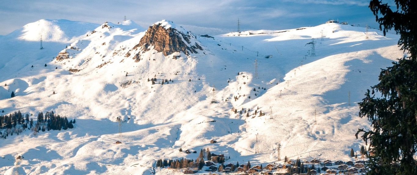 Snötäckta berg med klippor och en klar blå himmel.
