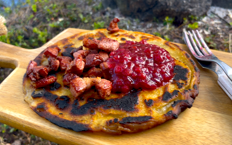 Pannkaka med bacon och lingonsylt på en träskärbräda.