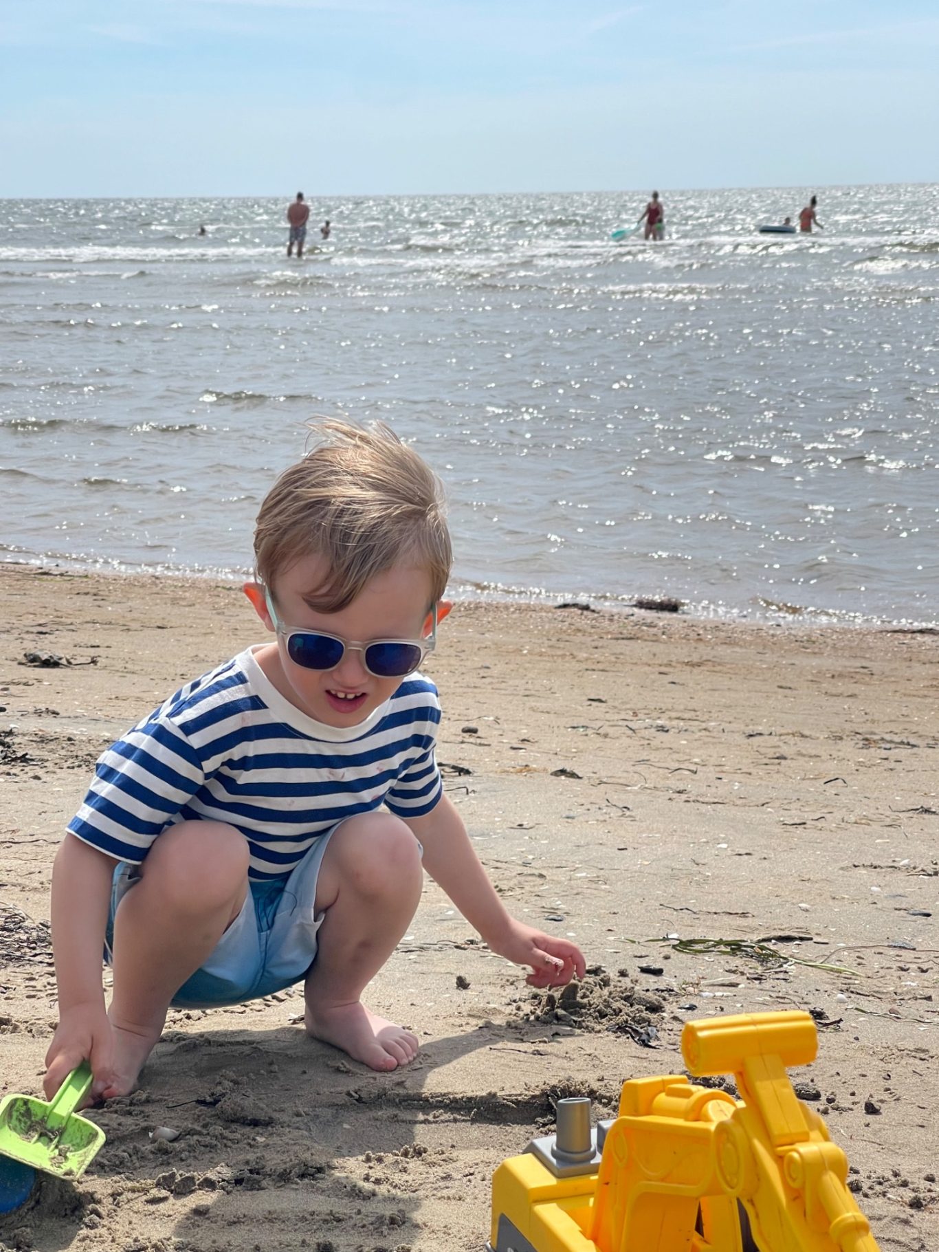 Skrea Strand Litet barn i randig tröja leker med sandslott vid stranden. Soligt väder.