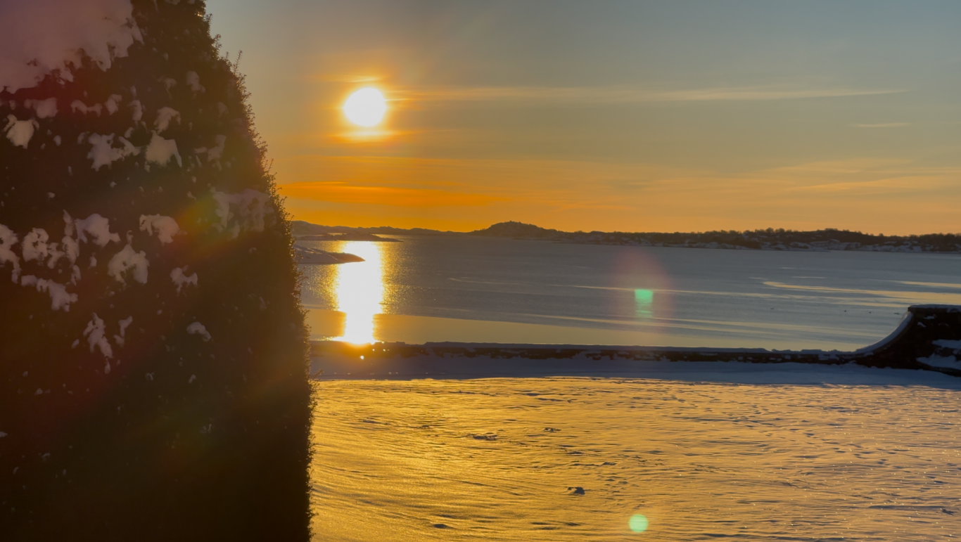 Solnedgång över Kungsbackafjorden Solnedgång över havet med reflektioner på vattnet och en klippa i förgrunden.