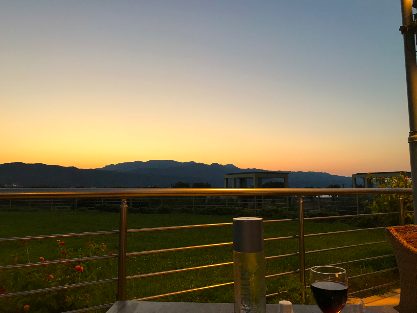 Sonedgång över hotellet Utsikt över bergen vid solnedgång med ett glas rödvin i förgrunden.