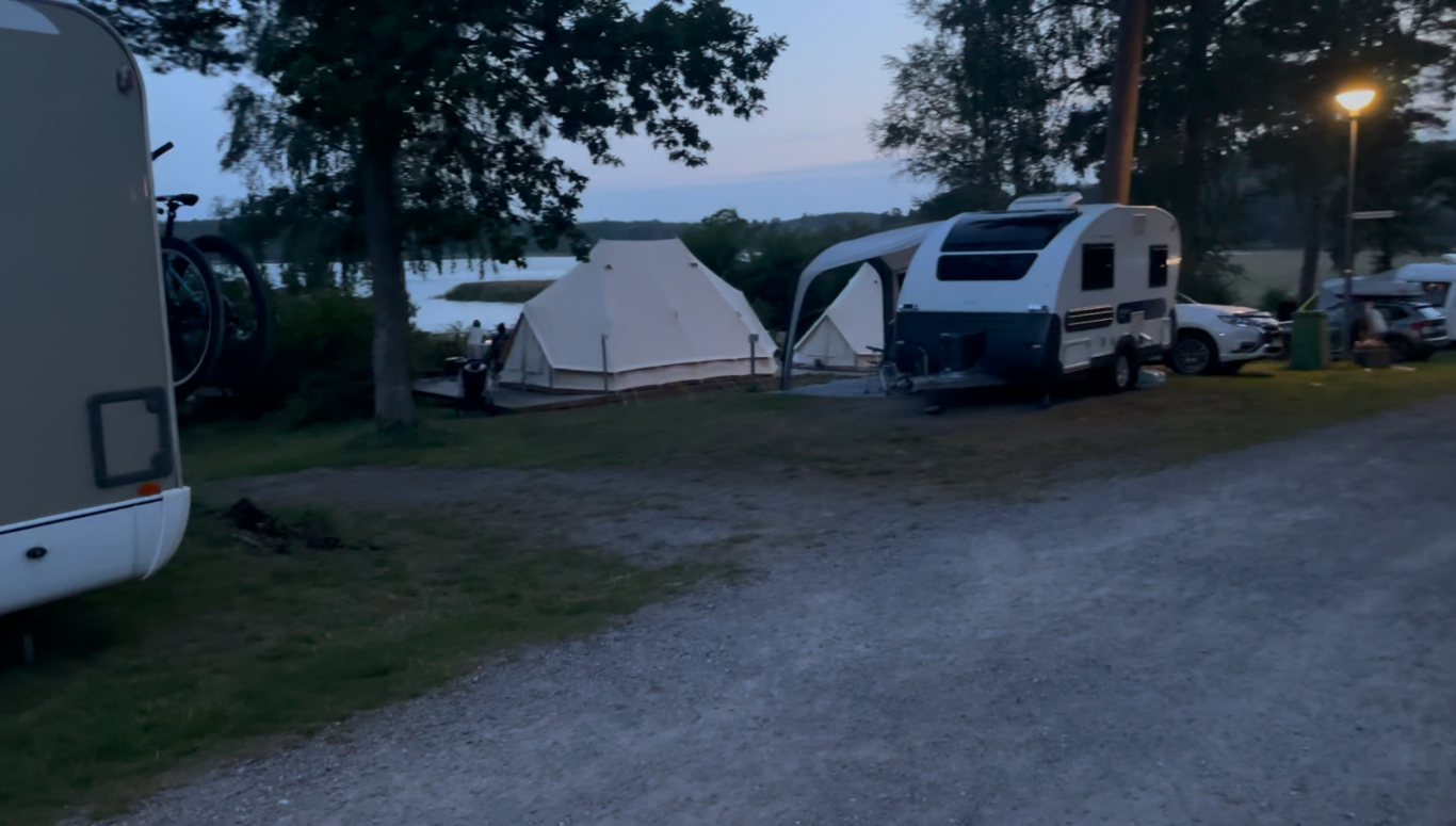 Glampingtält Campingområde vid sjön med tält och husvagnar i skymning.