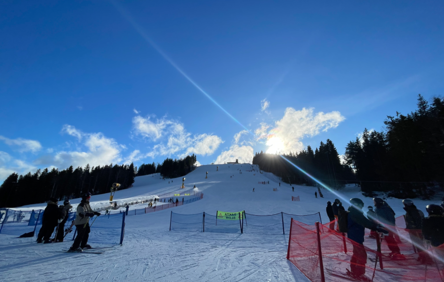 Storslagen vinterscen med skidåkare och snöklädda backar under en klarblå himmel.