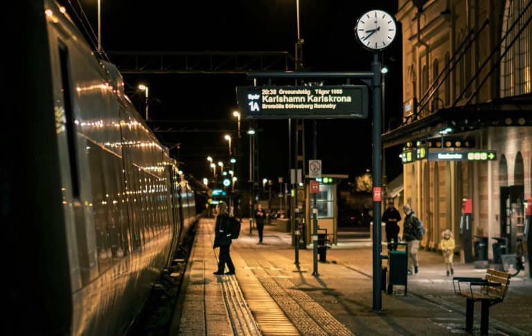 Tågstation på kvällen med mänskor och en klocka som visar tiden.