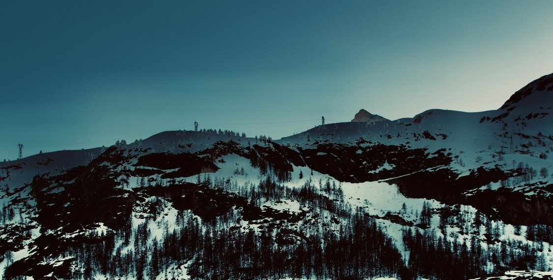 Snöklädda alpberg med mörkblå himmel i en lugn och kall vinterlandskap.
