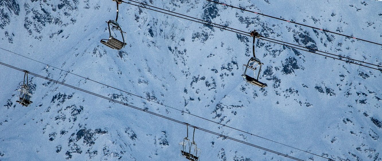 Skidliftar sväva över snötäckta fjäll och spår.