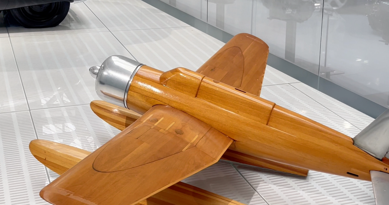 Flygplan Trämodell av ett flygplan med metallmotor, placerad på en ljus yta.