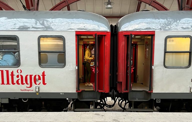 Två tågkupéer med öppna dörrar på en station, märkta "Tågtjänst".