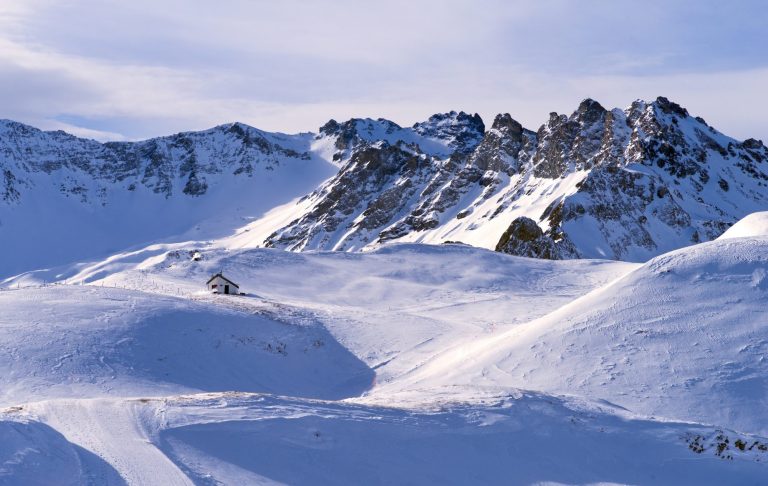 Snötäckta fjäll med klippiga alptoppar under en klar himmel.