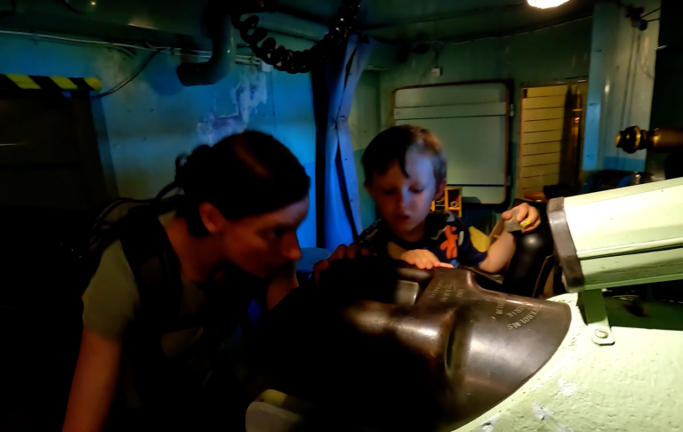 En vuxen och ett barn tittar på en maskin i dunkelt rum.