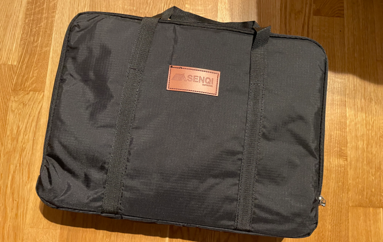 Svart bärväska med läderdetalj och handtag.