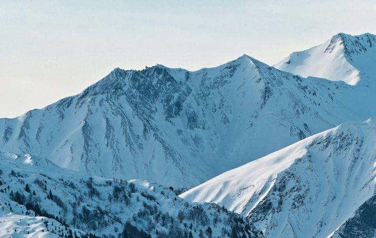 Snötäckta alpbergstoppar under en klar blå himmel.