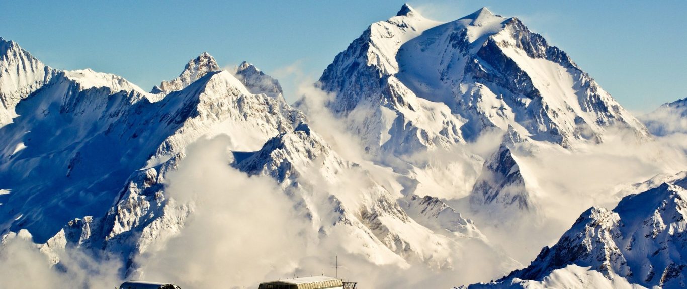 Snötäckta bergstoppar med dimma som sveper över dalarna.