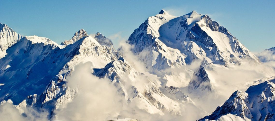 Gondol i Les 3 Vallees hänger i luften med snöiga berg i bakgrunden.