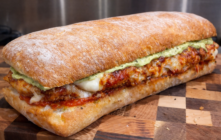 En ciabatta fylld med ost, tomatsås och grön pesto.