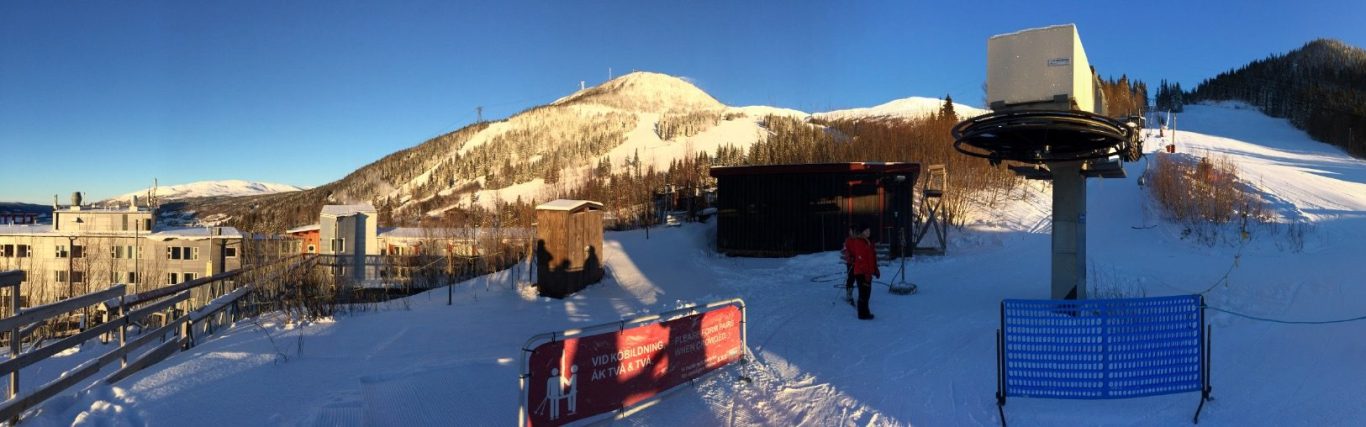 Vinterlandskap med snö, skidutrustning och berg i bakgrunden.