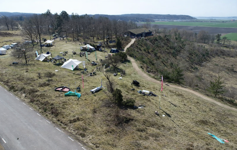 En Outdoorfestival Röjda områden med tält och fordon vid en grönskande kulle.