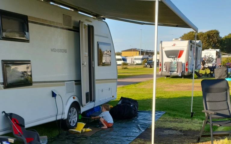 En husvagn på en campingplats med en barn som leker vid sidan av.