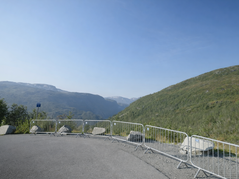 Utsikt över en dal med berg och klarblå himmel, avskärmad med stängsel.