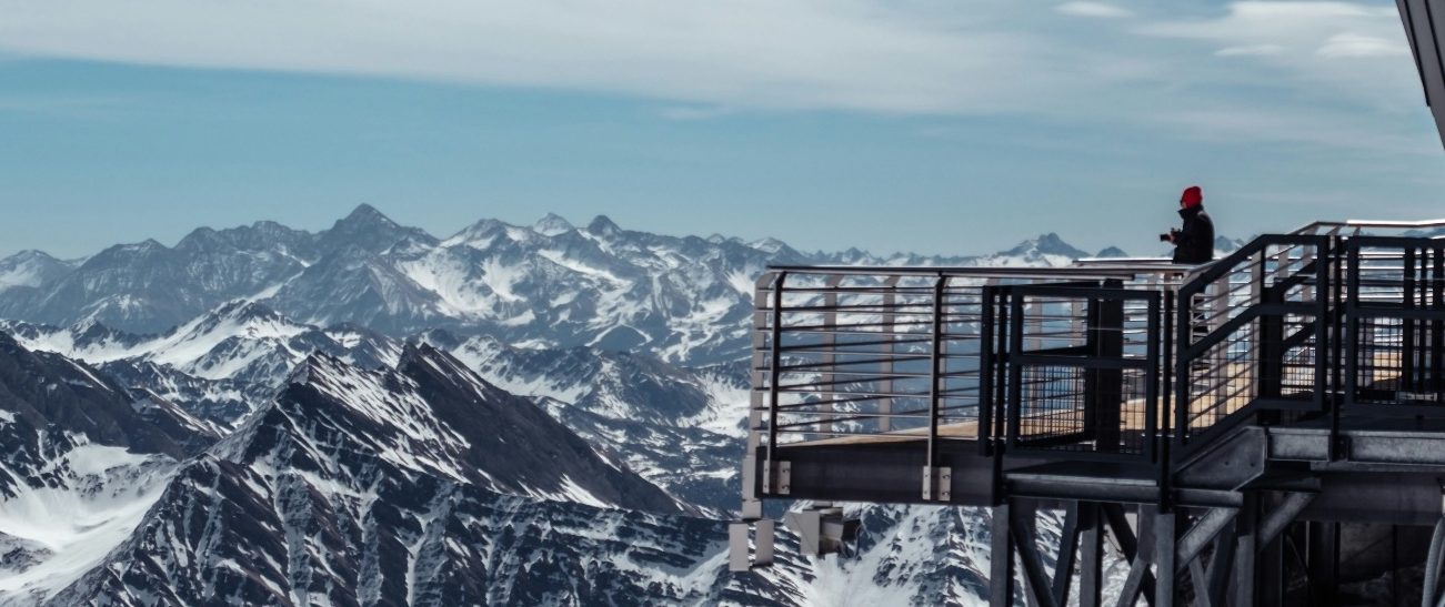 Courmayeur - Italien Utsikt över majestätiska berg med snö och en person på en plattform.