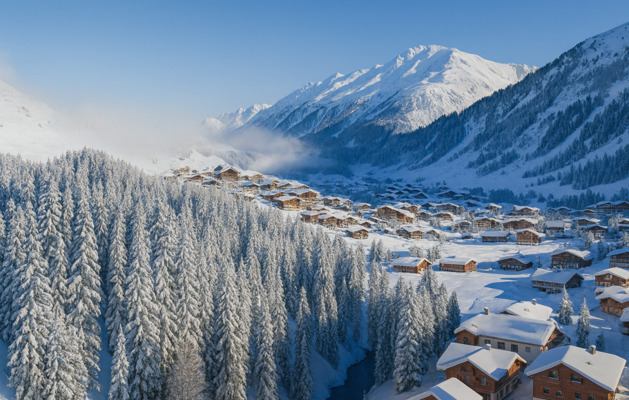 Illustration av Vintrigt landskap med snötäckta träd och alpfjäll, samt alpbyn Lech och Zürs  med timmerhus.