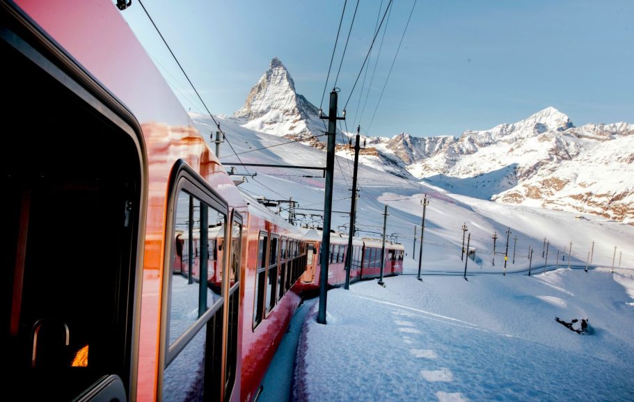 Röd tåg vid snötäckta berg, med utsikt över Matterhorn i bakgrunden.