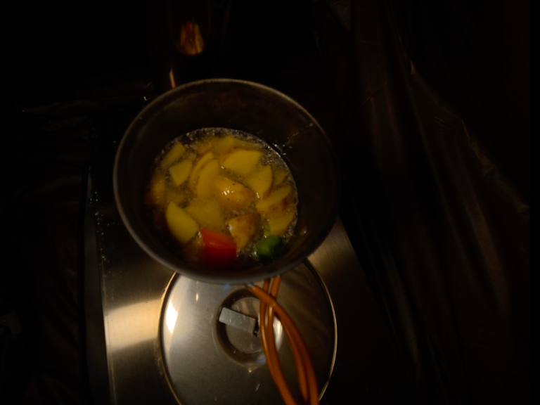 En kastrull med potatis och grönsaker som kokar på en spis.