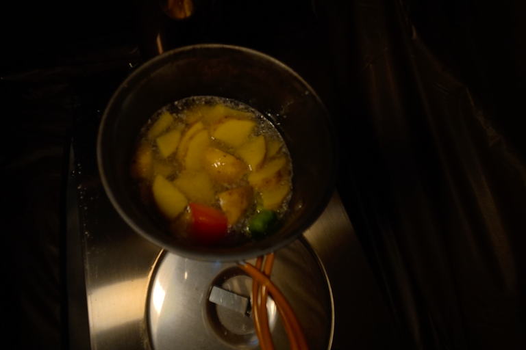 En kastrull med skivade potatisar och grönsaker kokar i vatten.