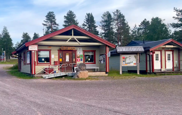 Färgglad byggnad med affärsskyltar och omgivande träd.