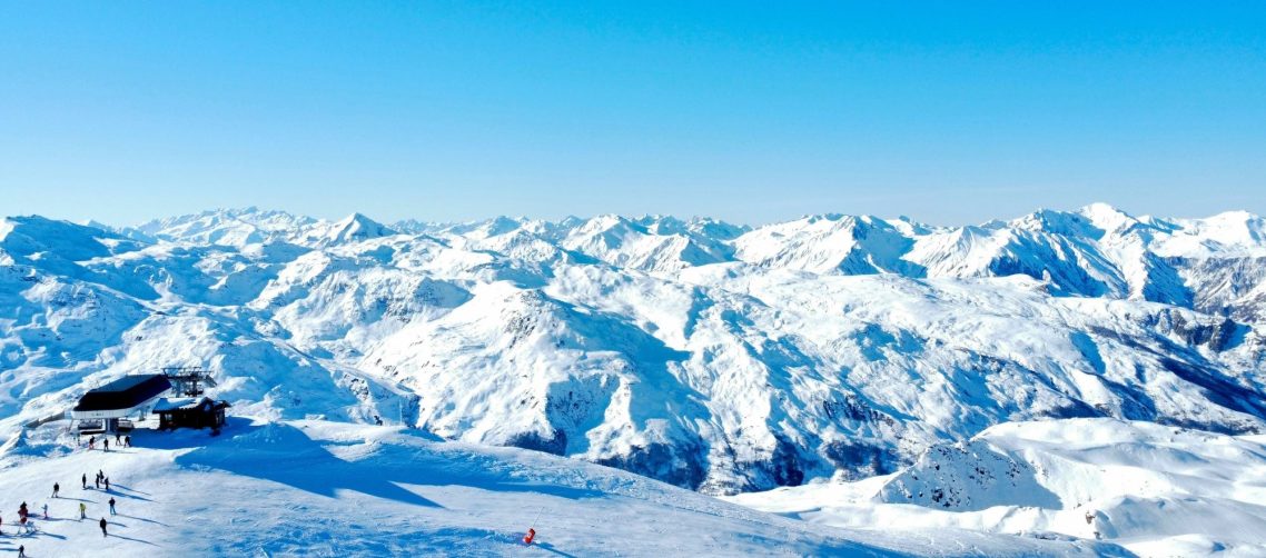 Gondol i Les 3 Vallees hänger i luften med snöiga berg i bakgrunden.