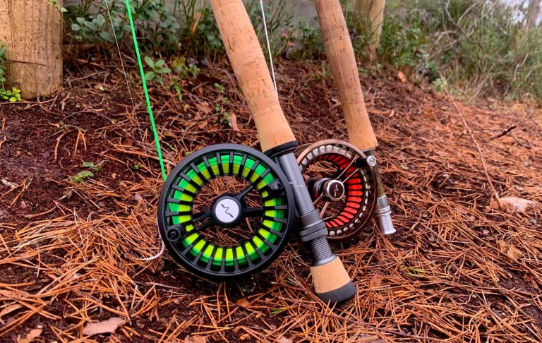 Flugfiskespön med rullar i grönt och rött, vilande på jordig bakgrund.