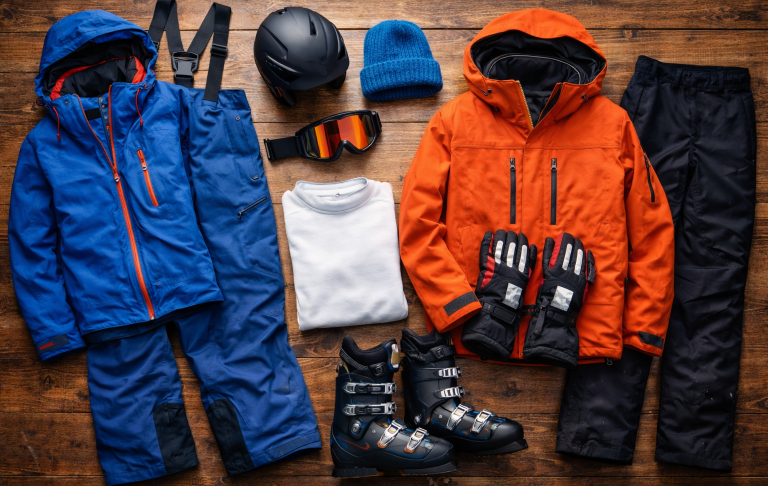 Skidkläder och tillbehör: två jackor, byxor, handskar, hjälm, mössa och pjäxor.