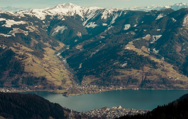 Utsikt över sjö och berg, med snöklädda toppar och grönskande dalar.