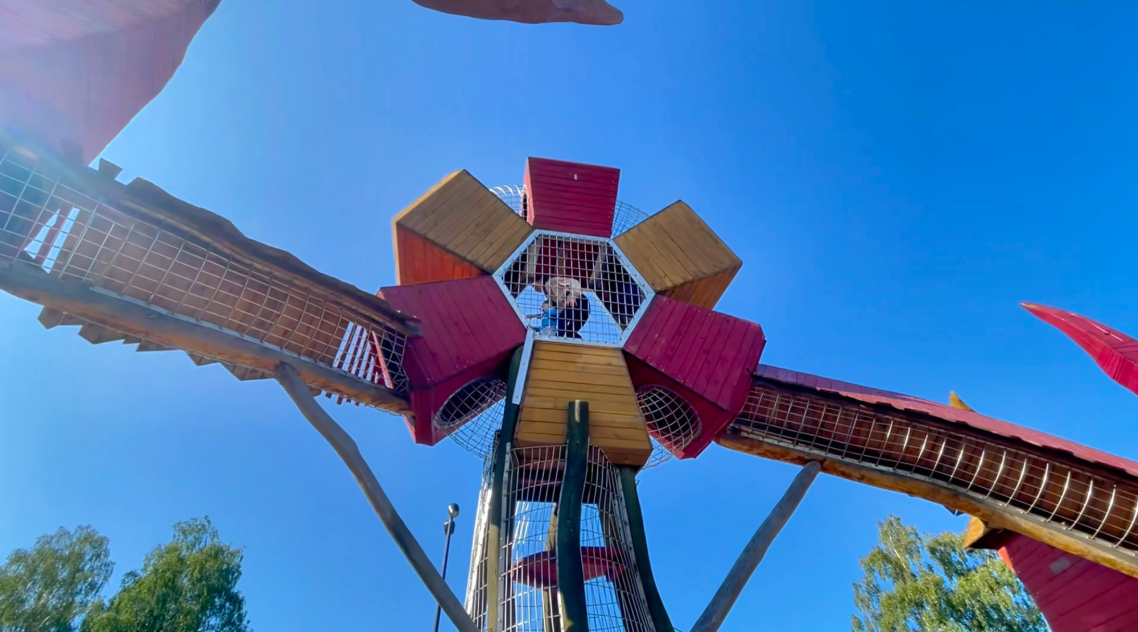 Vallarnas Friluftsområde Lekplatsen Lekplats med färgglada plattformar och rutschkanor under en klarblå himmel.