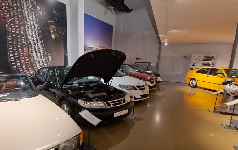Saab bilar på Saab Car Museum Utställning med flera bilar, varav en med uppfällt motorhuv.