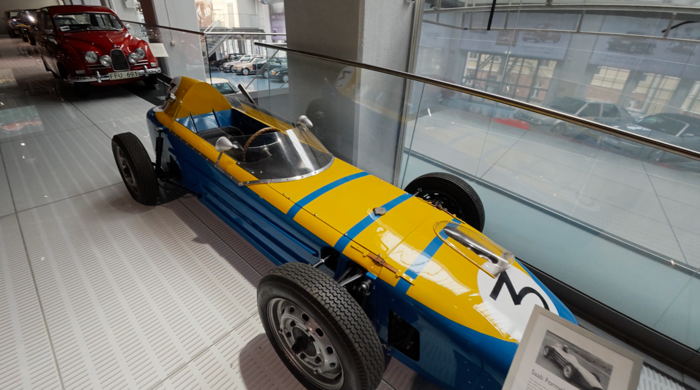 Saab Formel Jr Röd och blå racerbil i ett museum, med en slät, modern design.