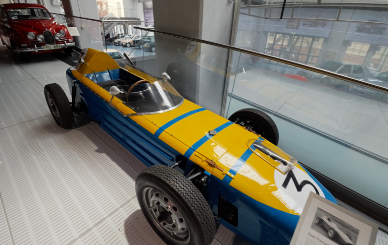 Saab Formel Jr på Saab Car Museum Racerbil med blå och gul målning, placerad i ett bilmuseum.