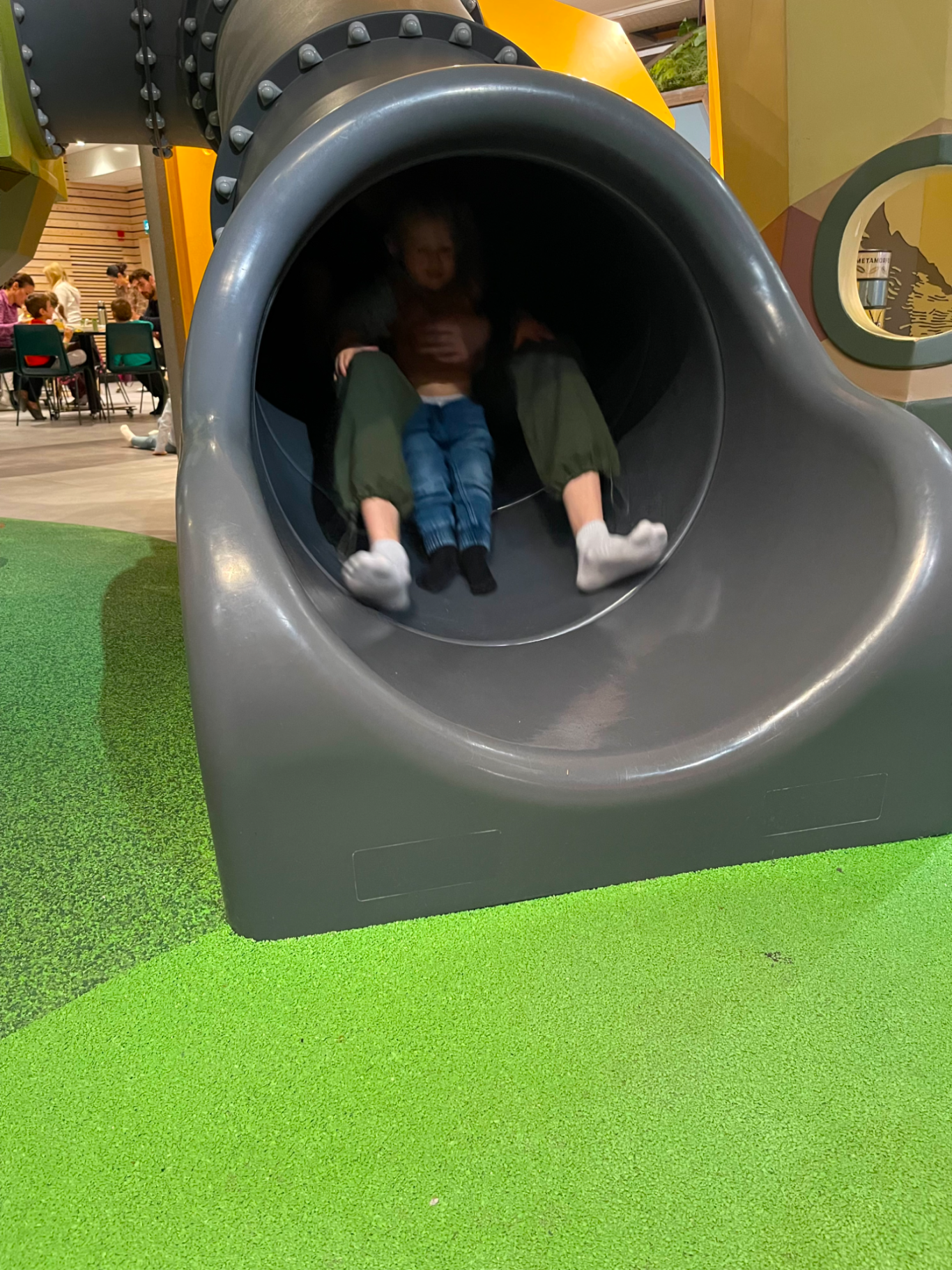 Rutschkana Barn sitter tillsammans i en rutschkana, omgivna av lekfulla färger.