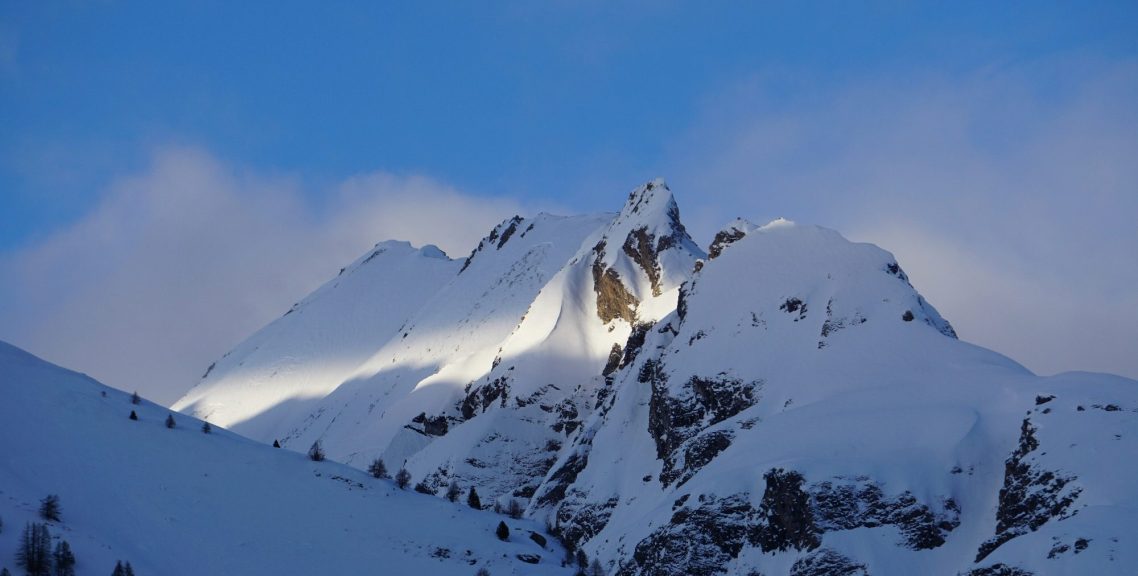La Thuile - Italien Snötäckta bergstoppar under en klarblå himmel med mjuka moln.