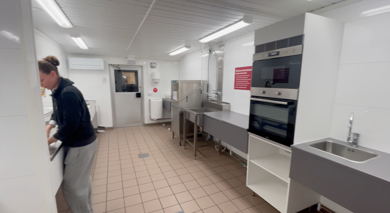 Servicehuset Kök Björkäng Kök med en person som lagar mat, moderna vitvaror och en ren, ljus miljö.