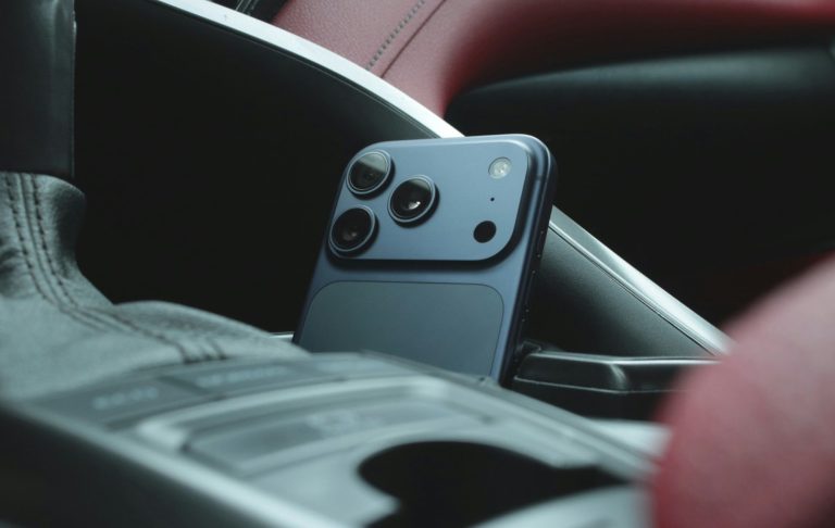 En mobiltelefon ligger i en bils armstöd, omgiven av röd och svart interiör.