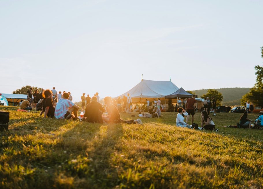 En Outdoorfestival Solig festivalstämning med människor och tält på en grön gräsmatta.
