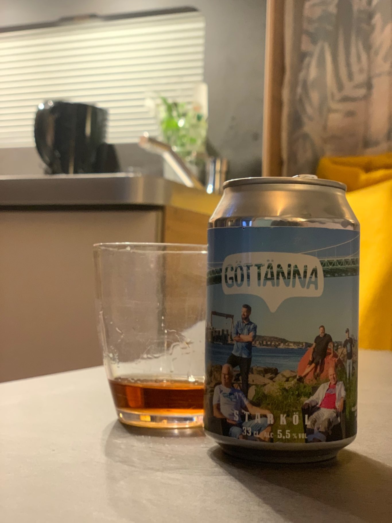 Stödbens-öl En ölburk med utsikt över en strand och en whisky i ett glas på ett bord.