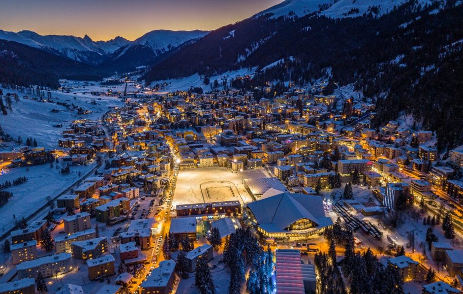 Vacker vintervy av en skidort med snöklädda berg och upplysta gator.
